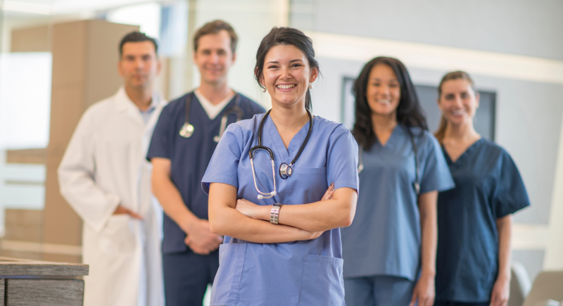 Six medical professionals standing in a V-shape, smiling