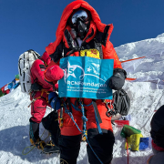 Rowena at top of Mount Everest holding RCN Foundation flag