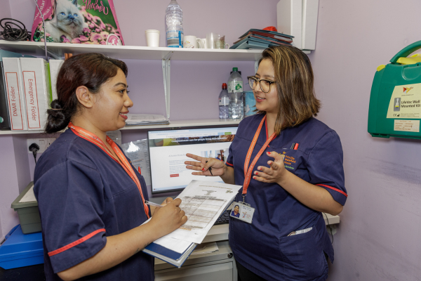 Two nurses talking at nurses station
