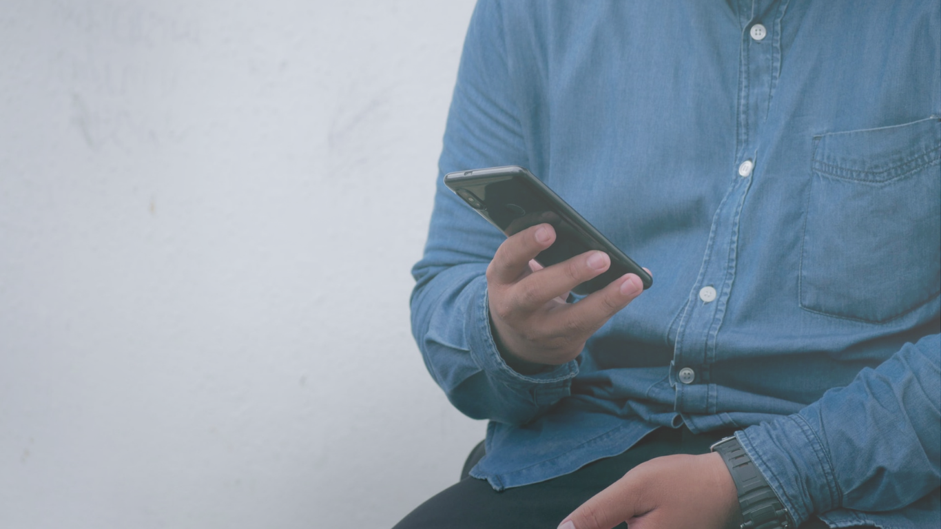 a man in a blue denim shirt checks his phone