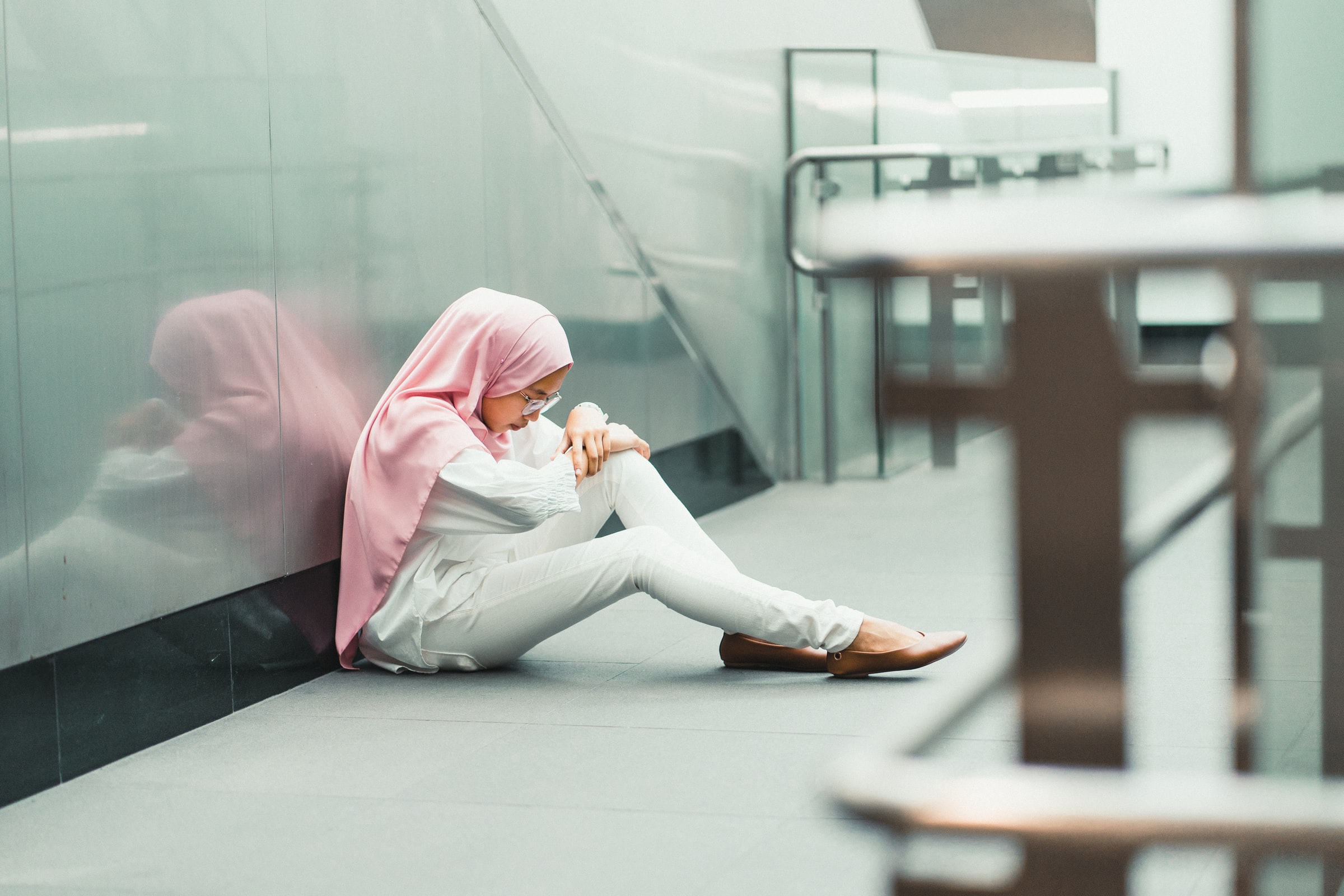 A girl sits on the floor of a corridor.  By Muhammad Faiz Zulkeflee image from Unsplash