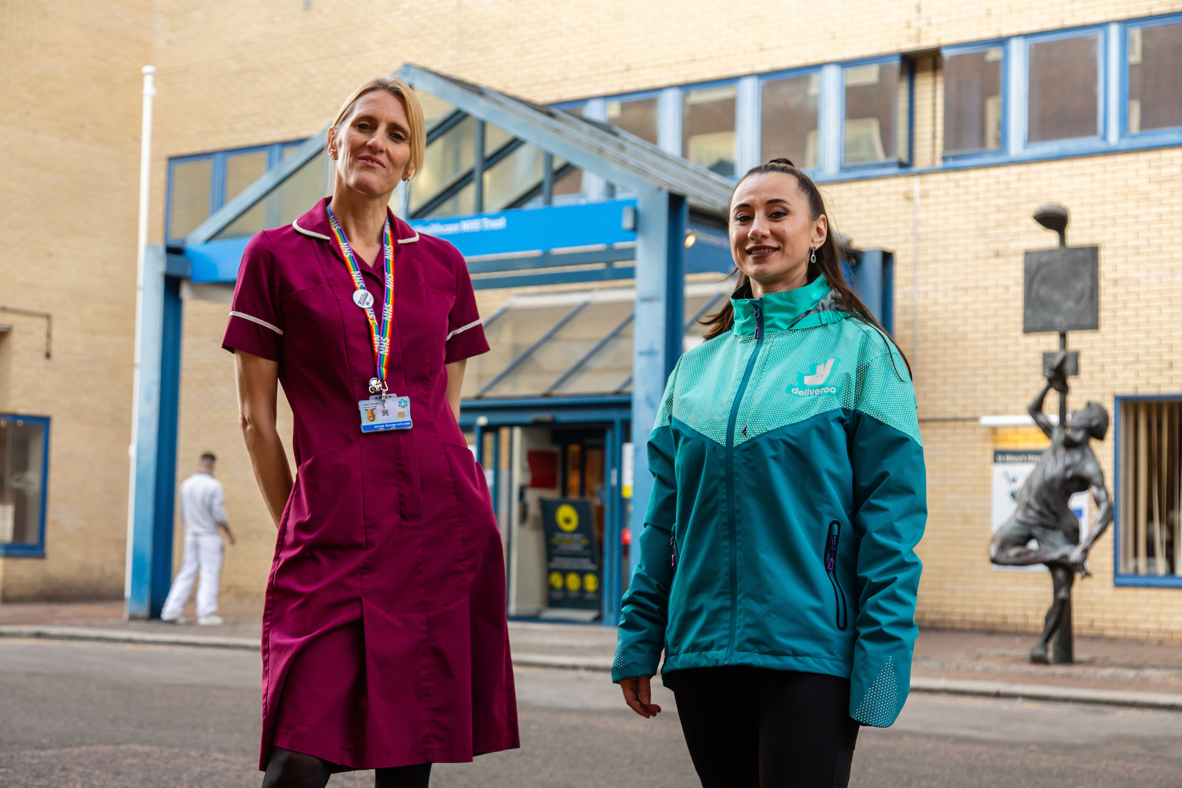 An NHS nurse and a Deliveroo driver stand outside a hospital