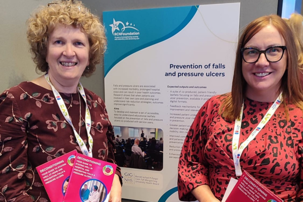 Two women stood in front of poster displaying their quality improvement research project 