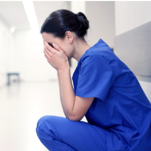 Nurse knelt down with head in hands Nurse knelt down with head in hands