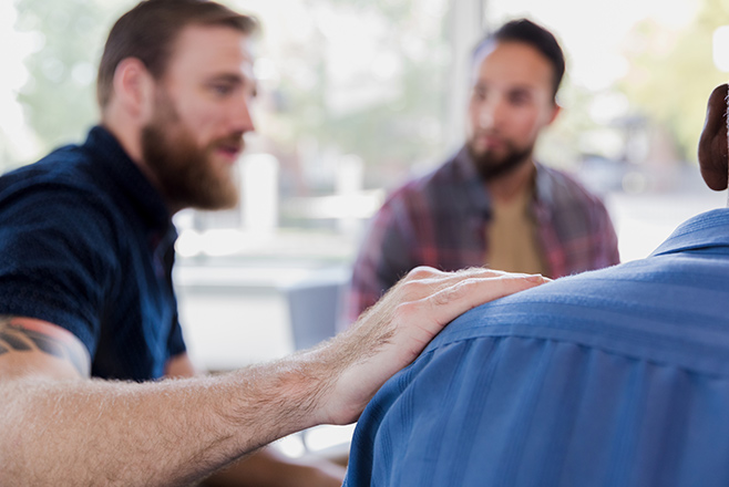 Man putting his hand on another man's shoulder