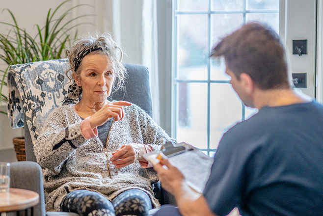 A man talking to an older lady who is sitting down