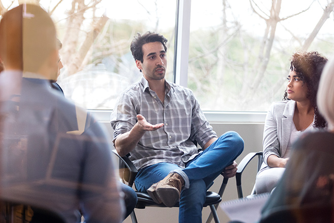 Man sat down talking with a group of other people