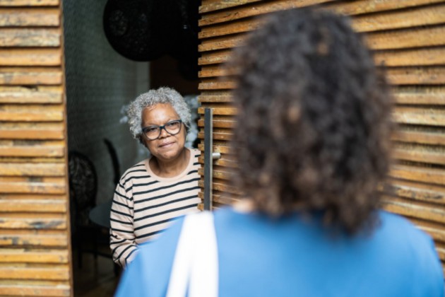 Older lady opening the door to a district nurse