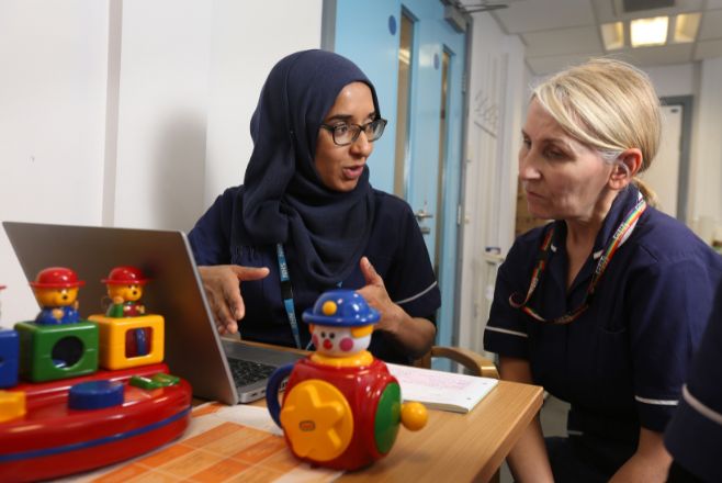 Two female nurses speaking to one another in child's play room