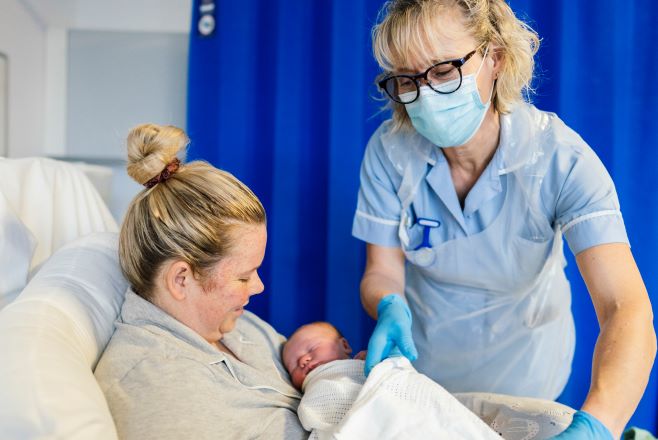 Nurse helping mother with newborn baby