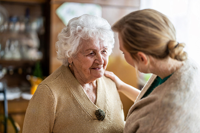 A caregiver putting her hand on an elderly woman's shoulder
