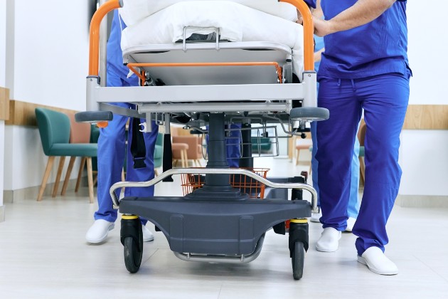 A patient on a bed being moved by two emergency care staff