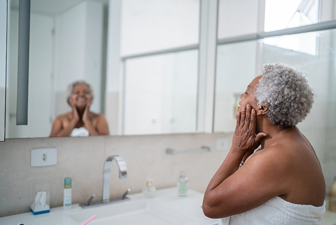 Woman washing her face in front of mirror