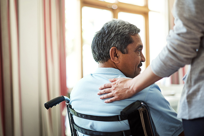 Man sitting in a chair with a man's hand on his back