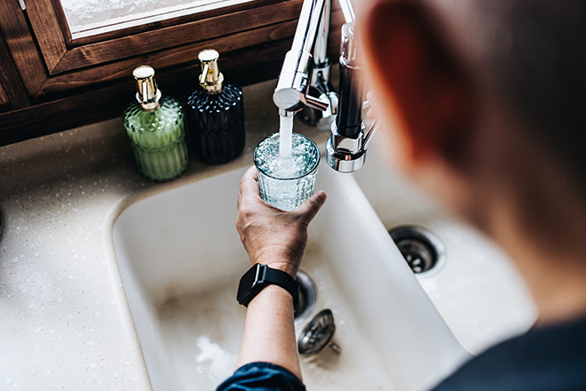 A person filling up a glass of water