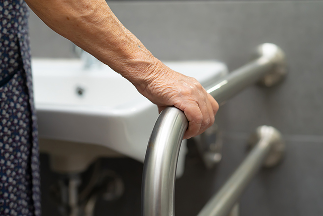 Woman holding onto a safety rail by a sink