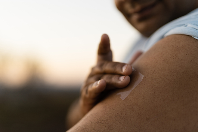 A person touching a plaster on their arm
