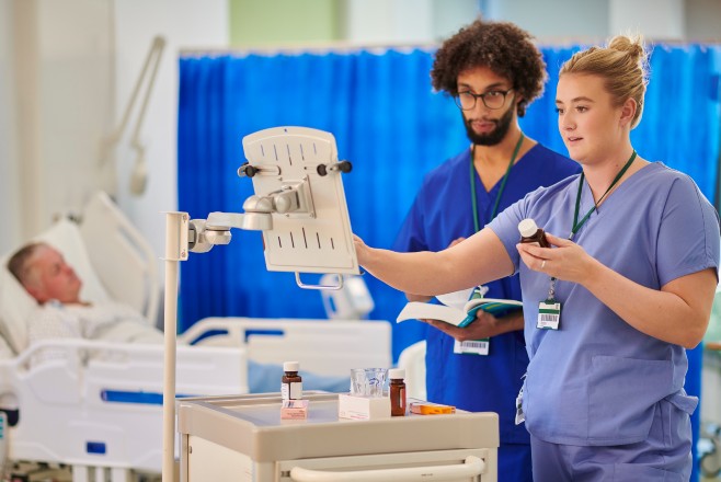 Two nurses recording a patients medication