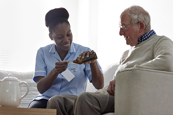 Nurse giving medicine to elderly man