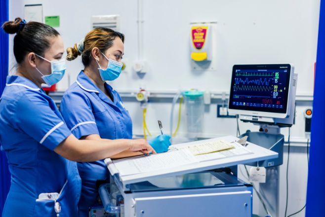 Two nurses working side by side in front of a monitor