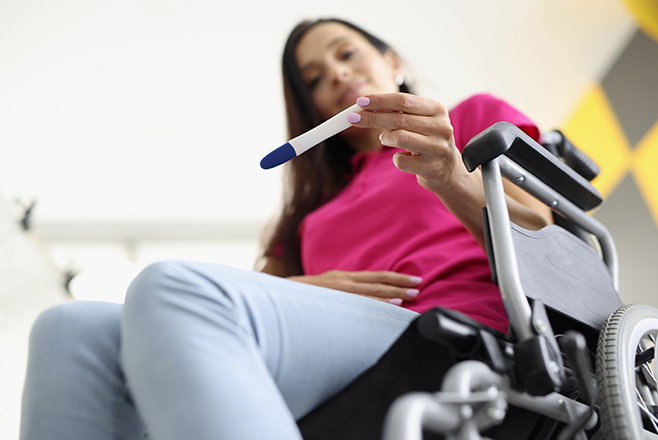 Woman sitting in a wheelchair looking at a pregnancy test