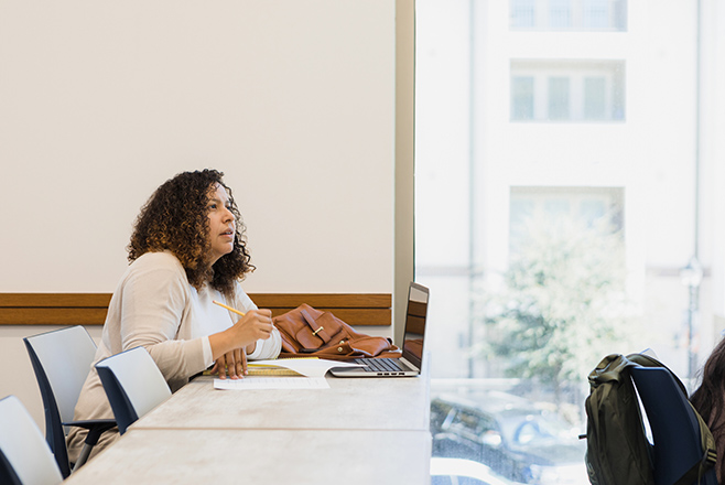 A woman sitting at a desk with a pencil and paper