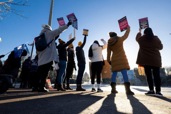 An image of nurses on strike together holding up strike signs. 