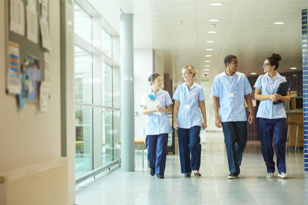 A group of nursing students talking and walking down a hall together