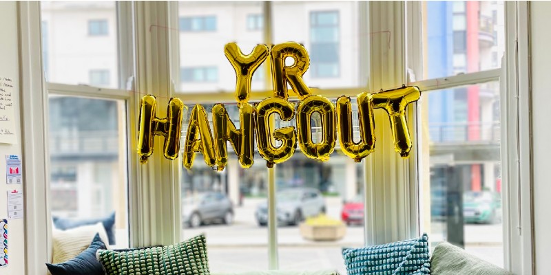 Balloons spelling "Yr Hangout" in window