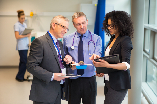 Three people in suits looking at documentation on a clipboard