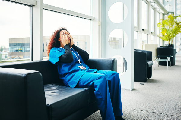 Image of nurse sitting down and holding hands to face
