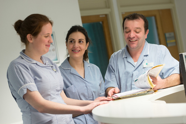 Three health care assistants talking to one another