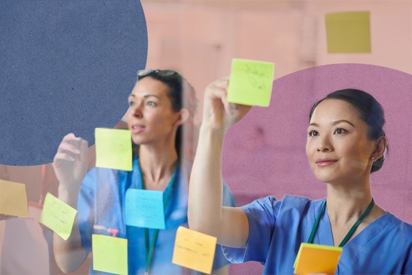 Two members of nursing staff placing sticky notes on a board
