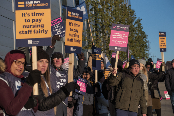 A group of ten nurses striking on a picket line