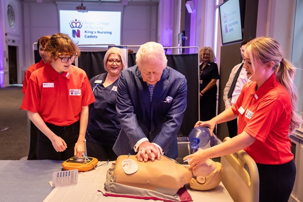 King Charles and two nursing cadets standing over a CPR manikin at RCN HQ