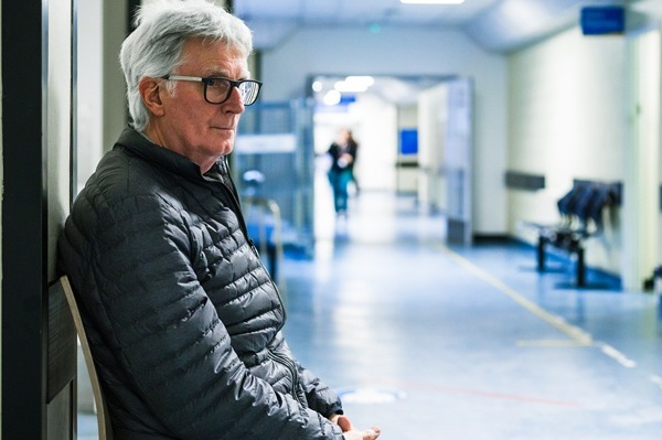 An elderly man sitting in a hospital corridor