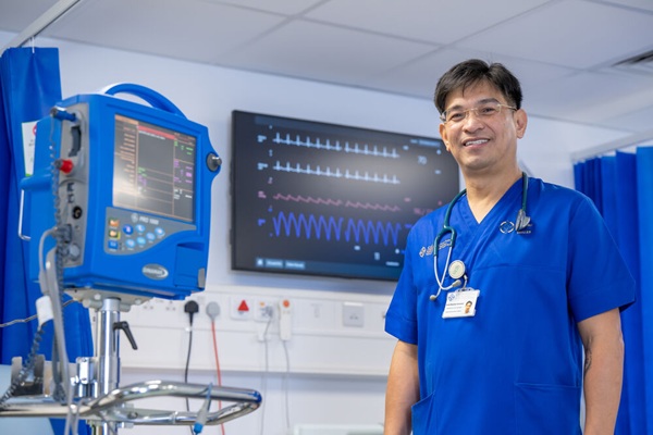 A smiling nurse standing in front of a hospital monitor