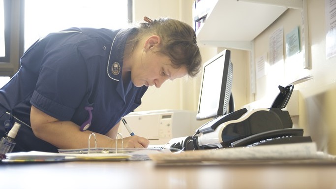 Female nurse writing something down telephone