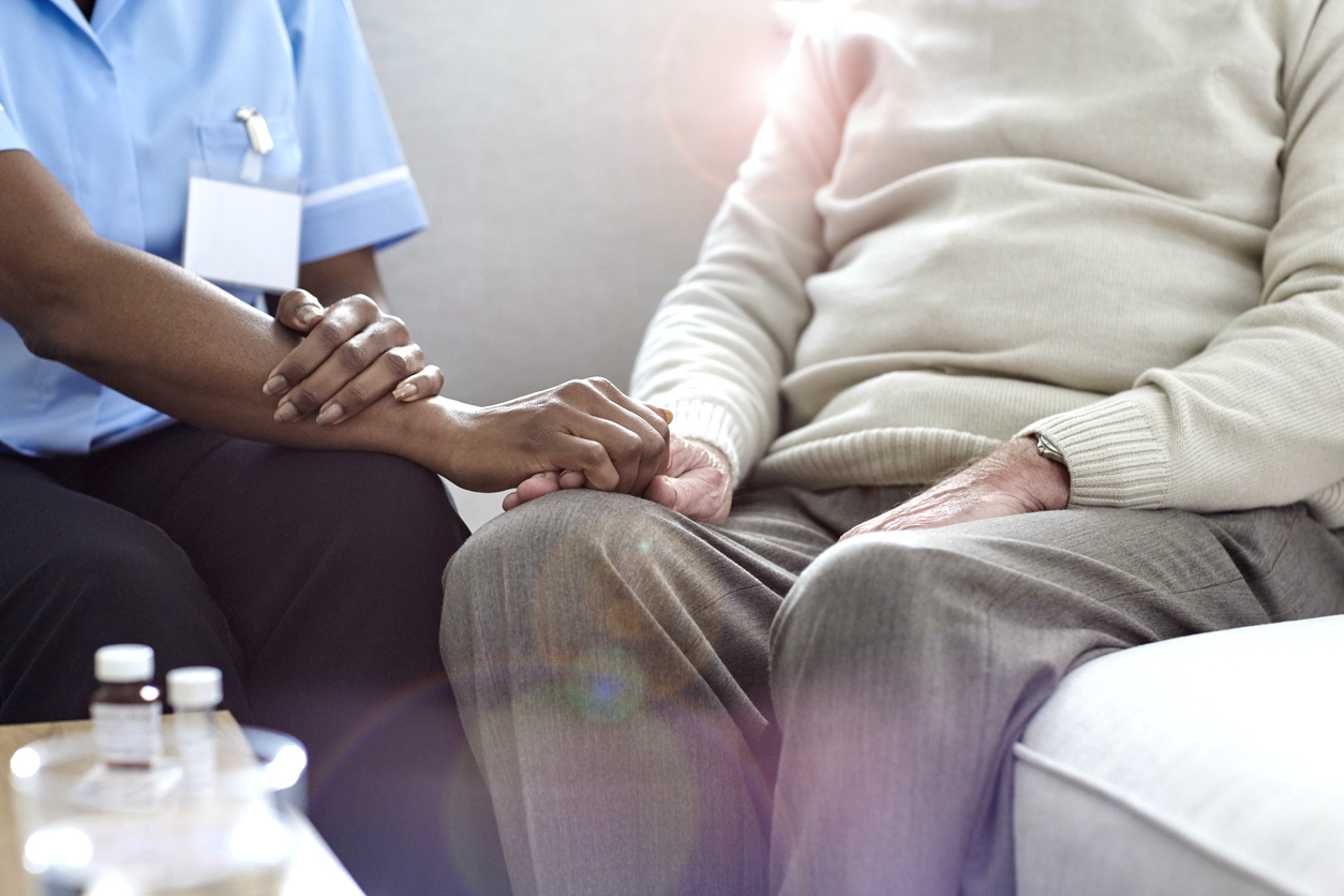 nurse holding hand of elderly man