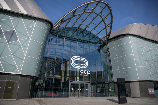 The exterior of a large, modern convention center featuring a curved glass facade and steel architecture.