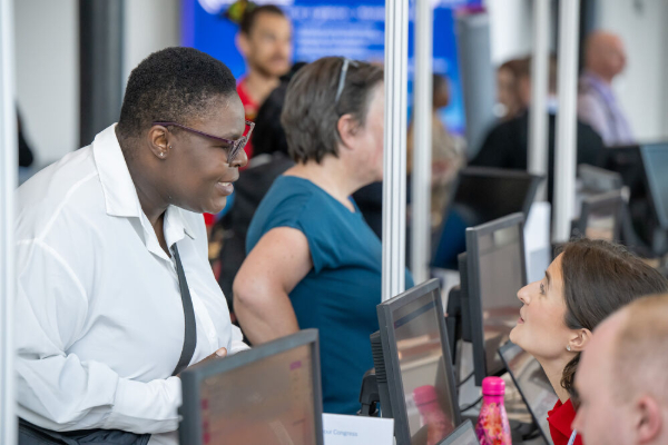 Several attendees standing around computer terminals or kiosks, appearing to check in or register.