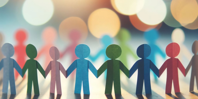 Multicoloured paper figures holding hands