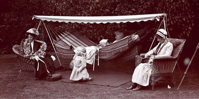 black and white photo of three women and a child relaxing outdoors in the early 1900s