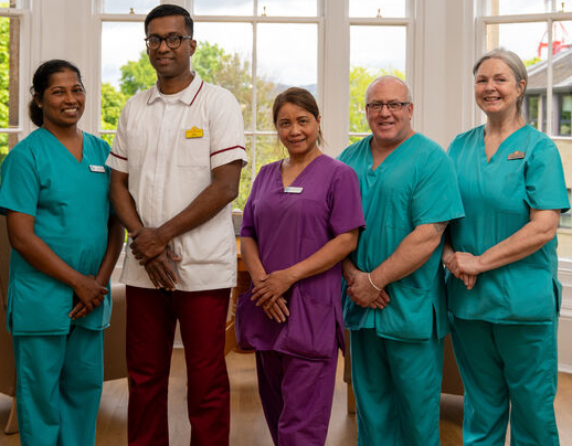 A nursing support worker and four colleagues pose together in a care home