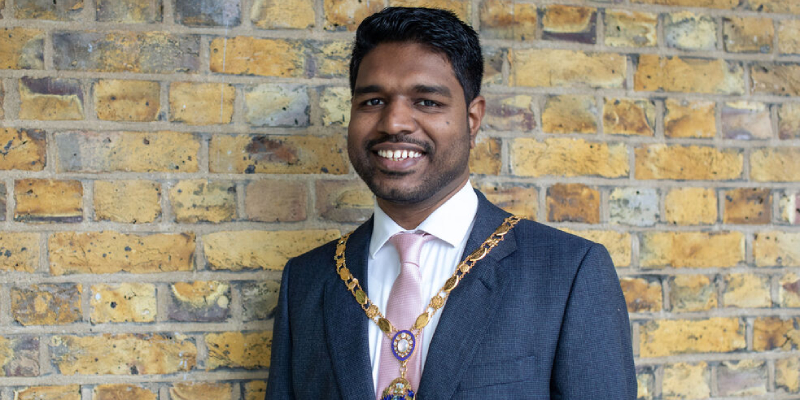 Bejoy Sebastian wearing a suit and tie with the RCN president ceremonial gold chain around him 800x400