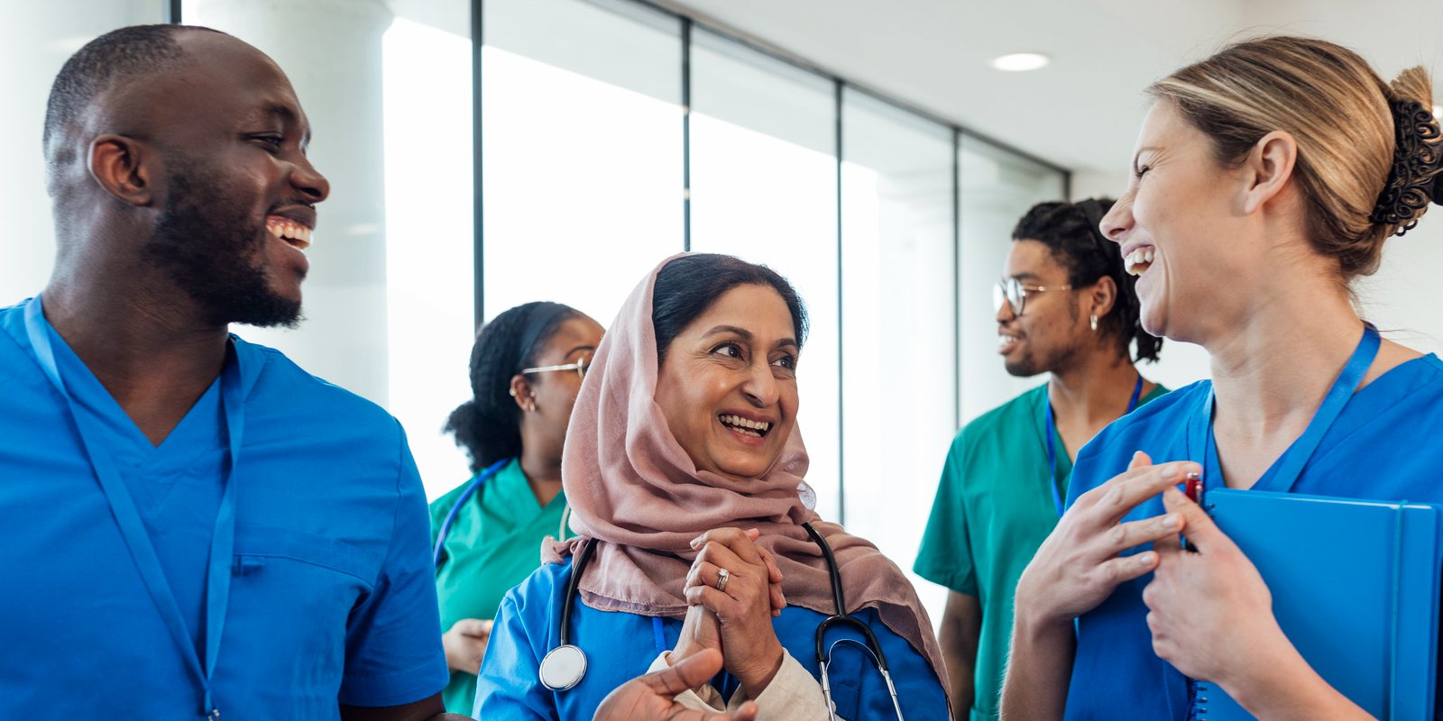 Diverse group of international nurses walking down a hospital corridor smiling and laughing together