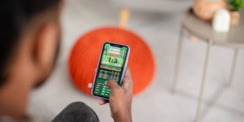 Man playing on his mobile phone looking at a green gambling screen Man playing on his mobile phone looking at a green gambling screen
