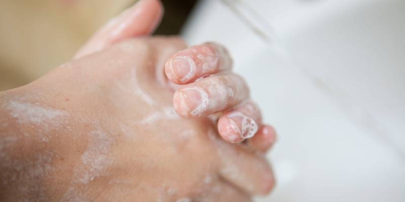 handwashing - two hands rubbing together in a sink covered in soap bubbles