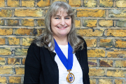 Carol Popplestone in front of a brick wall wearing Chair of Council medal