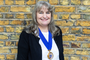Carol Popplestone in front of a brick wall wearing Chair of Council medal